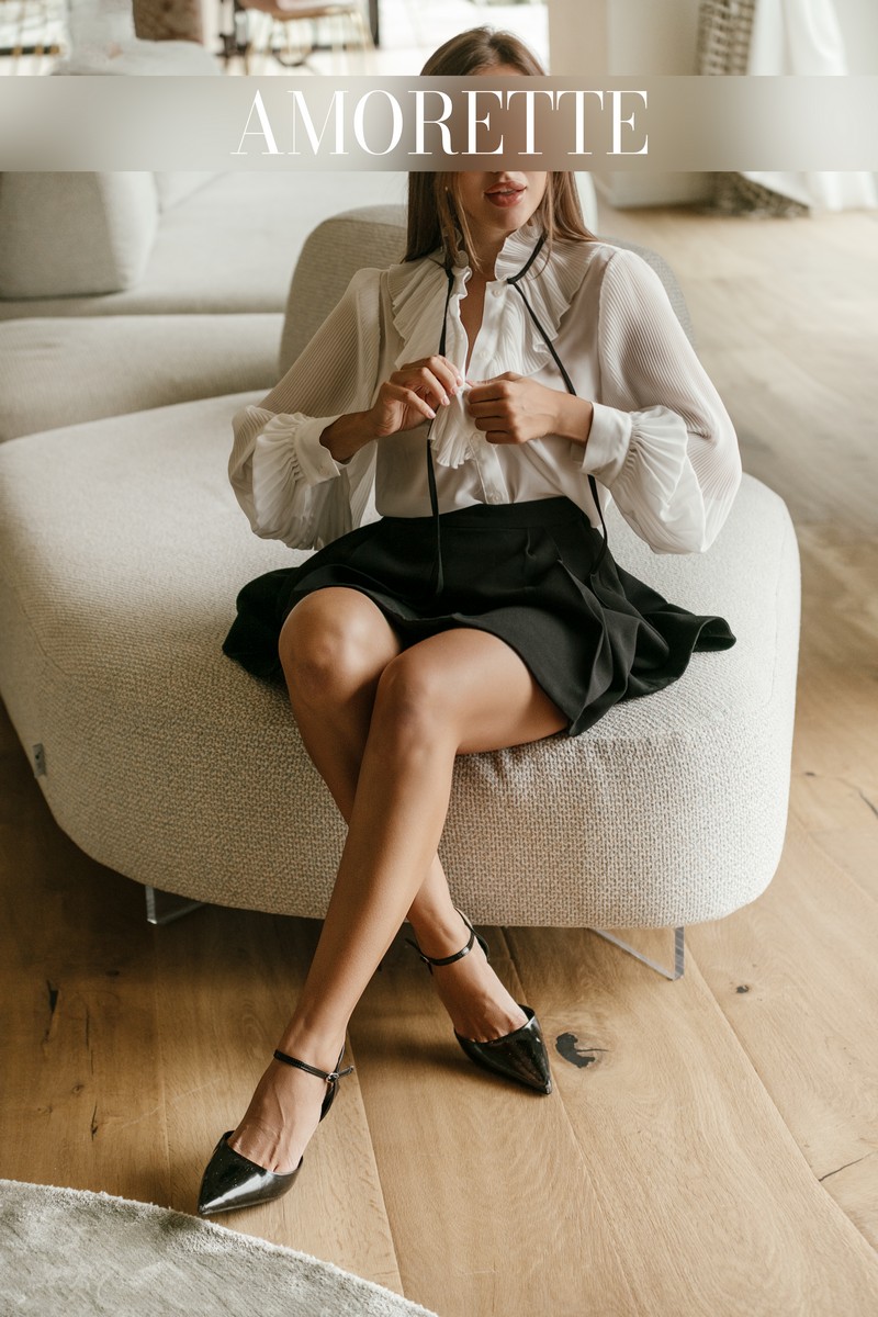Alina – Elite Escort Model from Frankfurt alina elite escort model from frankfurt shows her from the front while sitting on a white sofa wearing a elegant outfit, black skirt and white shirt, black high heels on her feets, her long bworn hair is open and smooth, high class escort, international, elite models, elite model, luxury, vacation, traveling