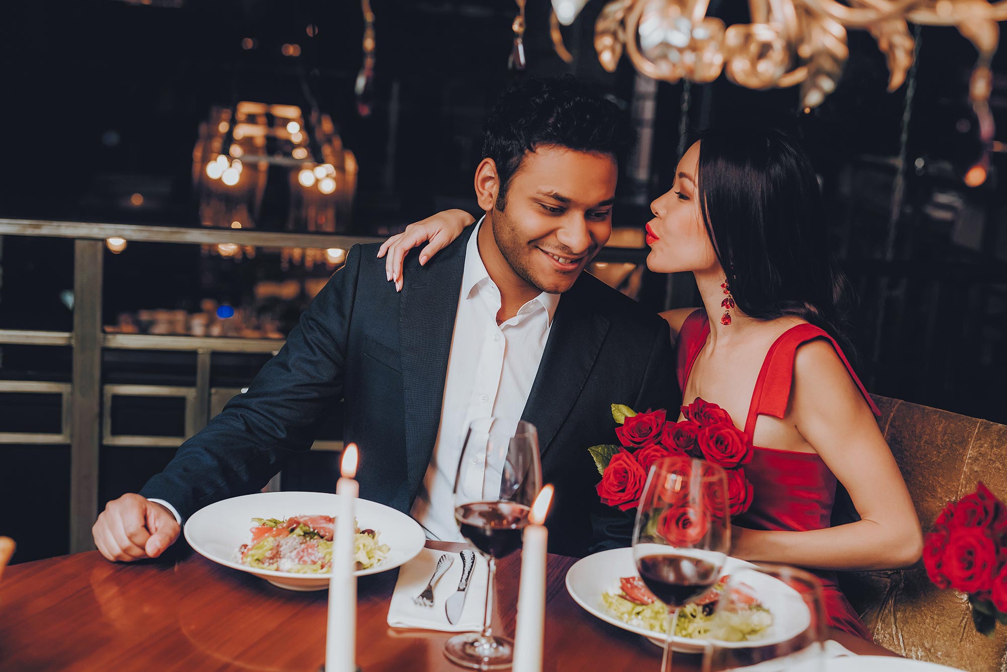 amorette international elite escort agency, high class escort service, dinner date, date, couple sitting in a restaurant at the candlelight dinner, red roses, elegant outfits, suit, red dress, red lips, black hair, young couple, luxury, traveling, vacation.