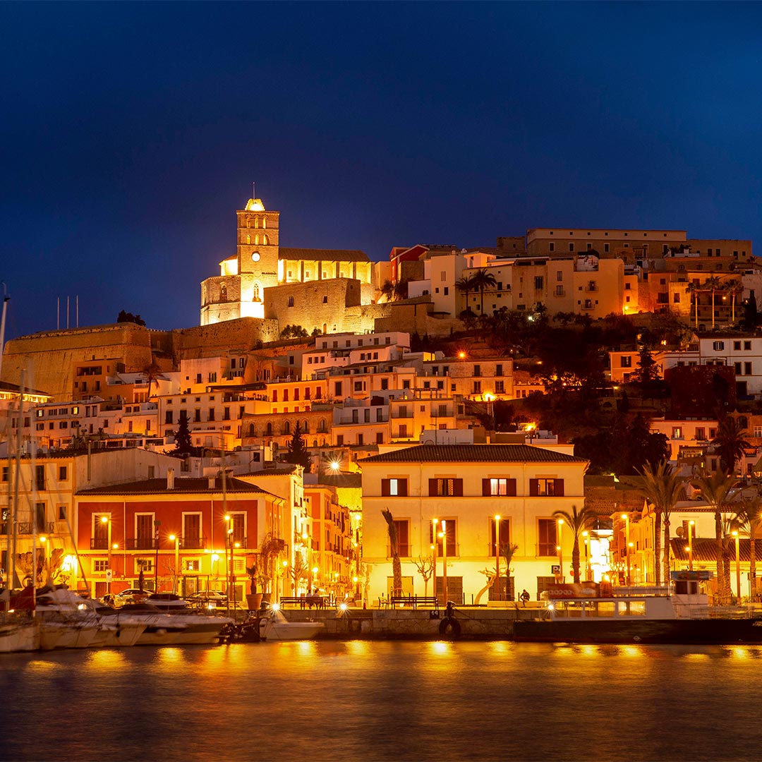amorette international elite escort agency offering high class escort service in ibiza, ibizy old town by night, old buildings by night, lightening lights, water, sea, night, summer, vacation, romantic, high class escort, elite escort, traveling, luxury